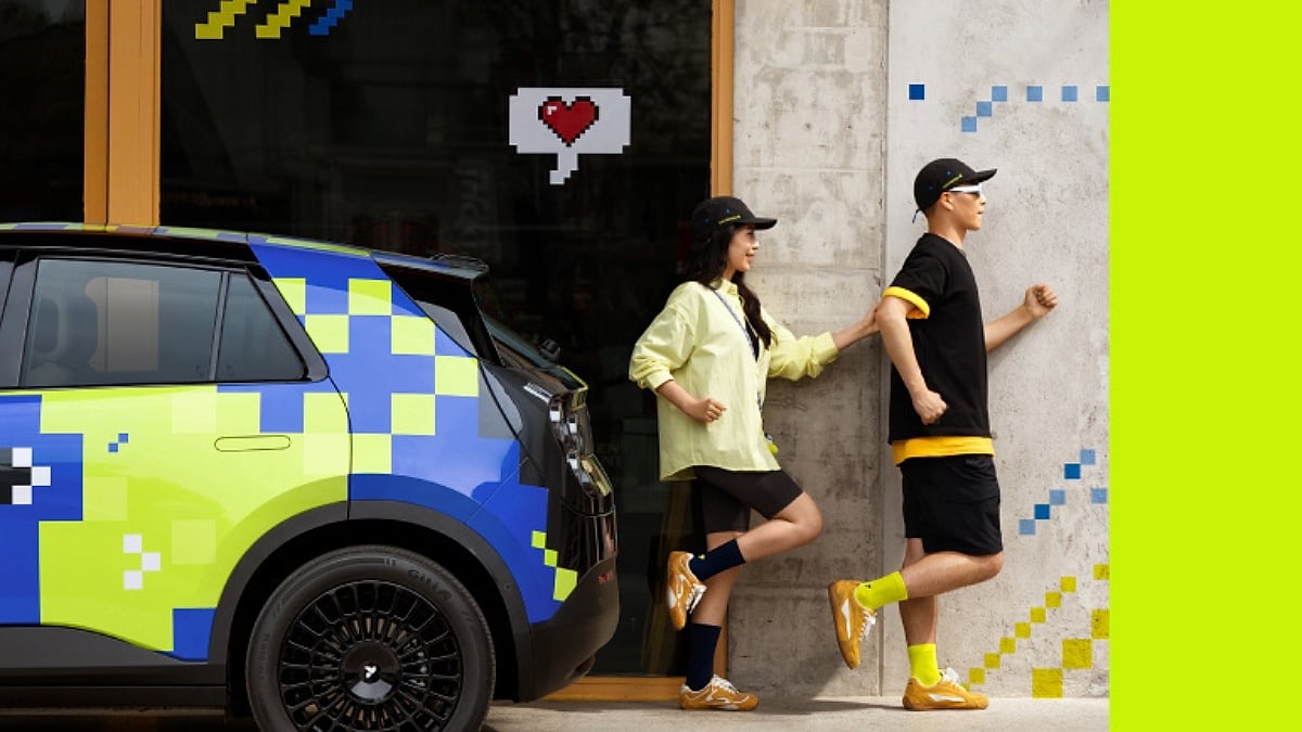 Two people stand beside a vibrant, pixel-art styled Firefly car.
