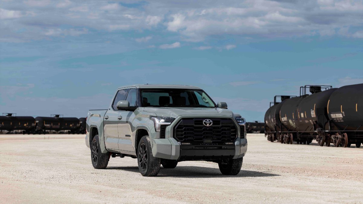 2022 Toyota Tundra in pale green, parked on dusty ground with black train cars in background