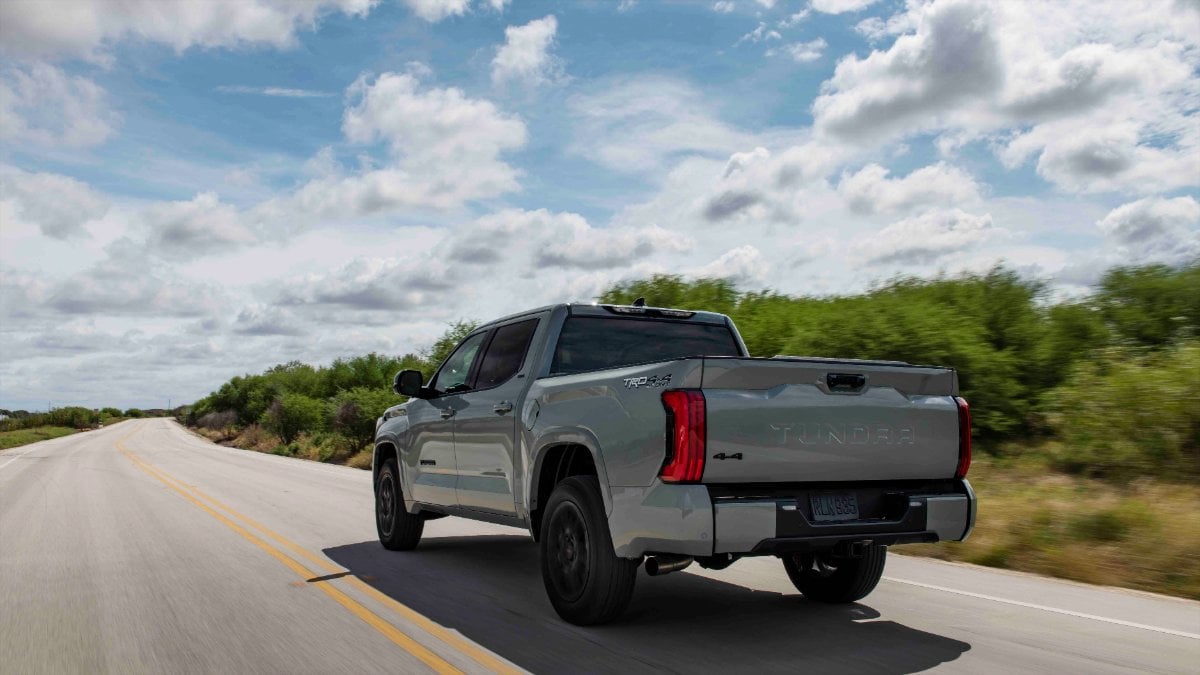 Silver 2022 Toyota Tundra SR5 TRD driving on rural highway with cloudy blue sky and green landscape