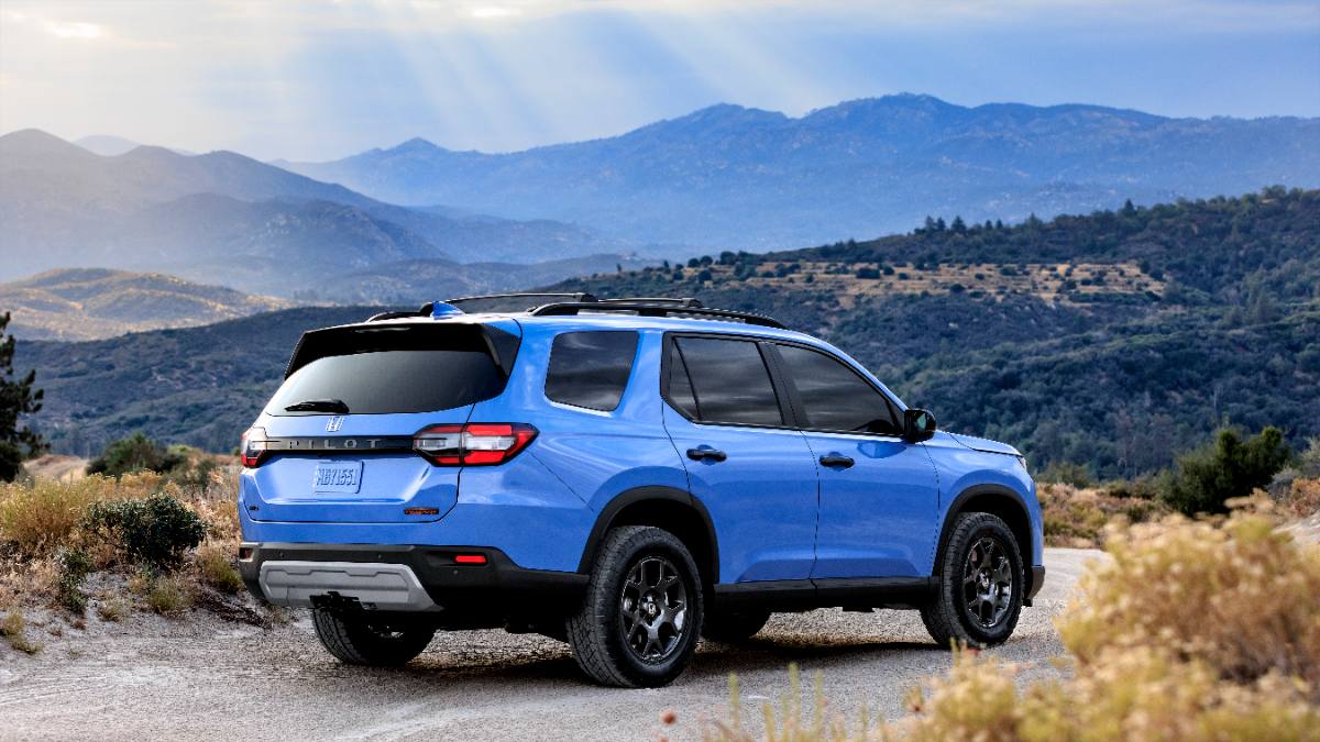 Blue Honda Pilot SUV parked on rocky mountain trail with misty mountain range in background