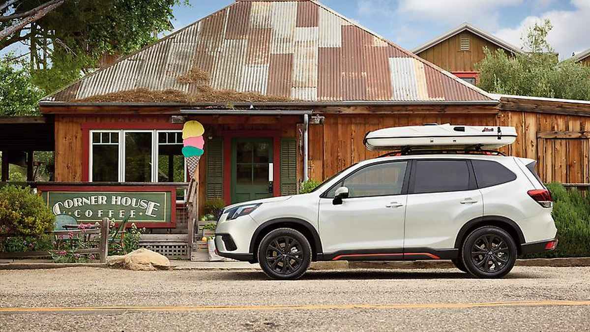 A white SUV parked beside a rustic coffee shop with a corrugated roof, featuring a colorful ice cream sign in front.