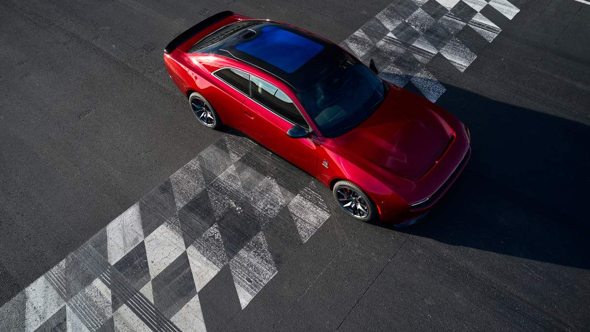 A sleek red sports car is positioned over a checkered finish line on an asphalt track, highlighting its aerodynamic design.