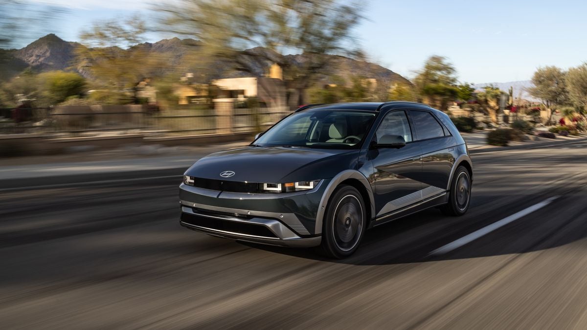 A Hyundai Ioniq 5 accelerates on a scenic road with mountains in the background, showcasing its modern design.