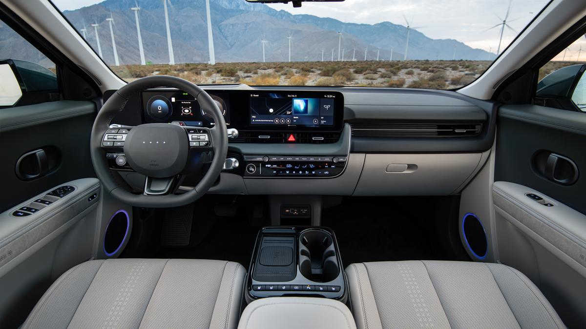 Interior view of a 2025 Hyundai Ioniq 5 featuring a sleek dashboard, digital displays, and comfortable seating amidst a desert landscape.