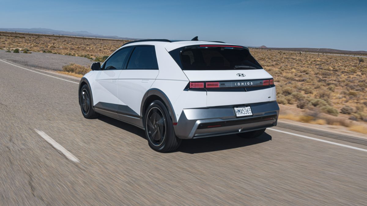 White Hyundai Ioniq 5 driving on desert highway with mountains in background