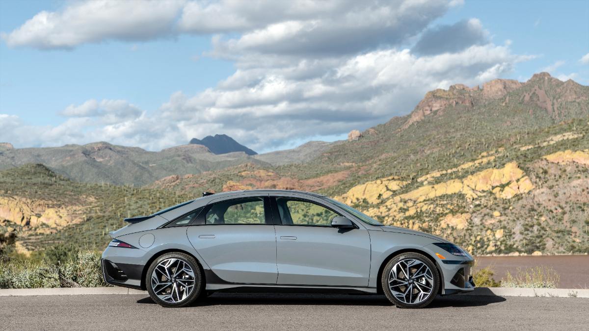 Silver 2025 Hyundai Ioniq 6 sedan parked on roadside with rugged mountain landscape backdrop