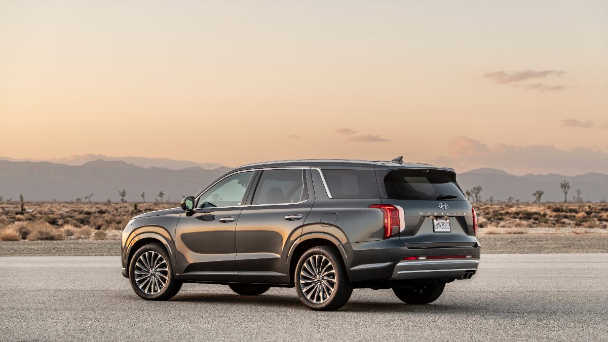 Dark gray 2026 Hyundai Palisade SUV parked on desert road with mountain silhouette at golden sunset