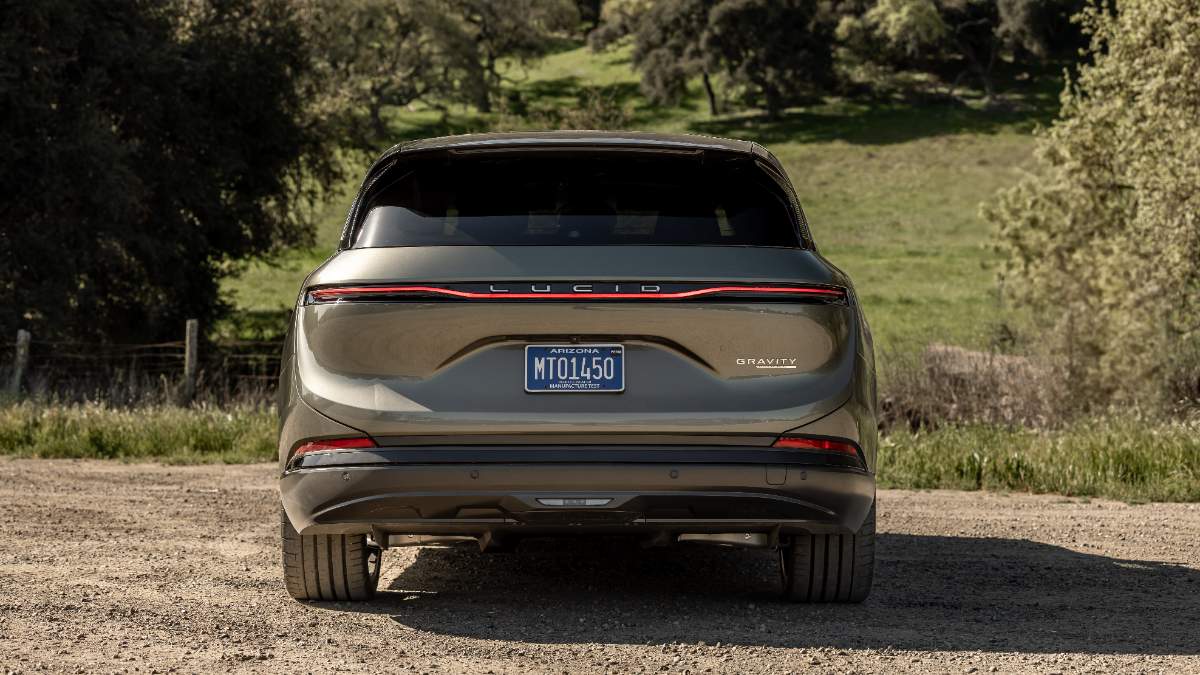 Lucid Gravity electric SUV parked on dirt road with grassy landscape and trees in background