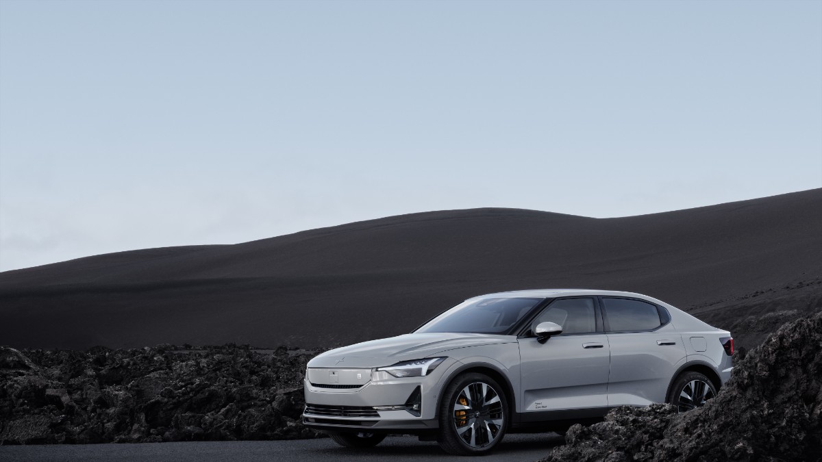 2025 Polestar 2 in silver, front three-quarter view, showcasing distinctive headlights and large wheels against a rocky landscape.