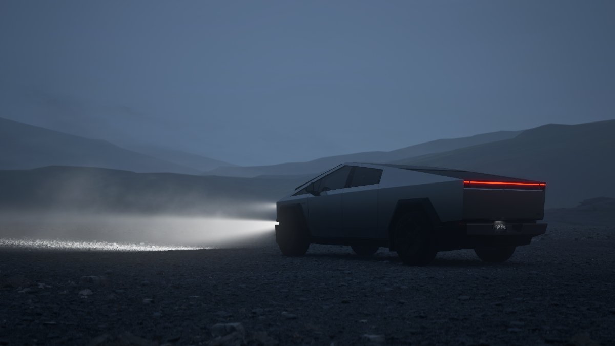 Tesla Cybertruck with headlights illuminating misty mountain landscape at dusk, angular silhouette with red taillight