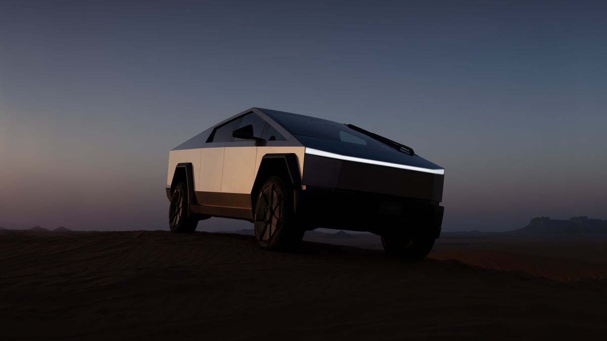 A 2025 Tesla Cybertruck, silhouetted against a dusk sky, parked on sandy terrain with dramatic lighting highlighting its angular design.