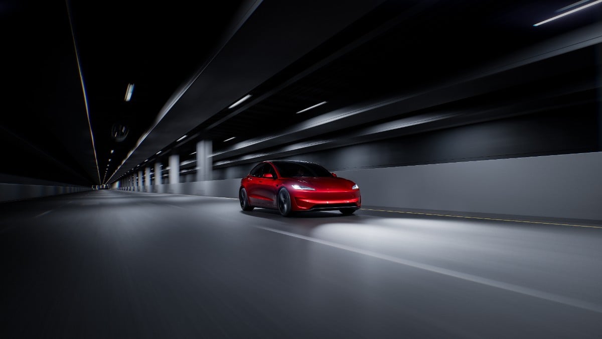 A sleek red electric car speeds through a well-lit, modern tunnel, emphasizing its dynamic design and motion.