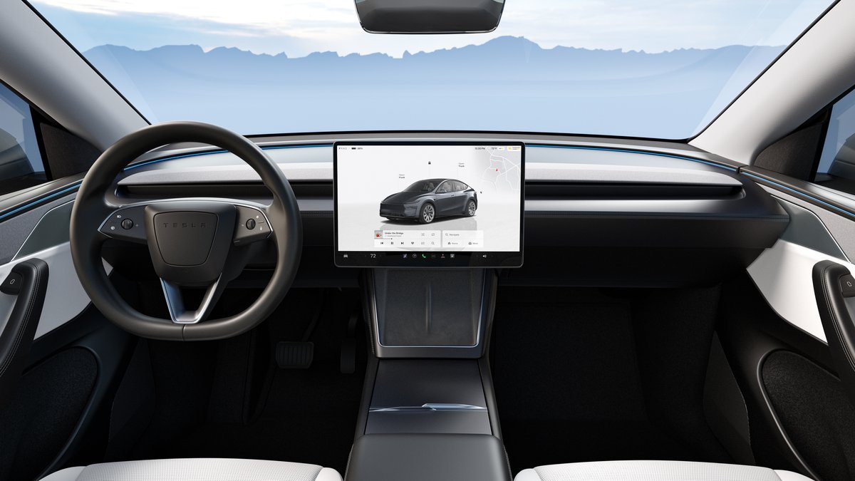 Interior view of a Tesla Model Y Juniper, featuring a modern design with a sleek steering wheel and a large touchscreen display.