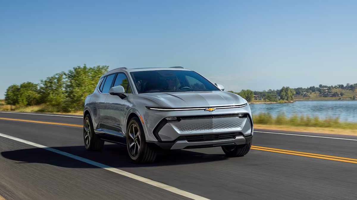 Alt text: Gray 2025 Chevrolet Equinox EV electric SUV photographed at front three-quarter view with scenic mountain backdrop.