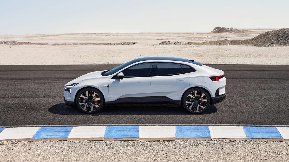 A sleek white electric car shown from the side, parked on a racetrack with a barren landscape in the background.