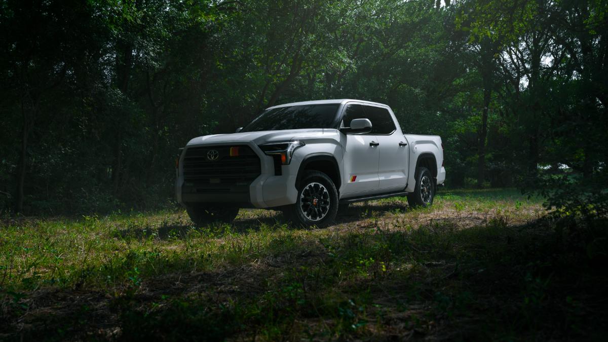 2022 Toyota Tundra in white, photographed at three-quarter front angle in a wooded setting, featuring black trim and distinctive alloy wheels.