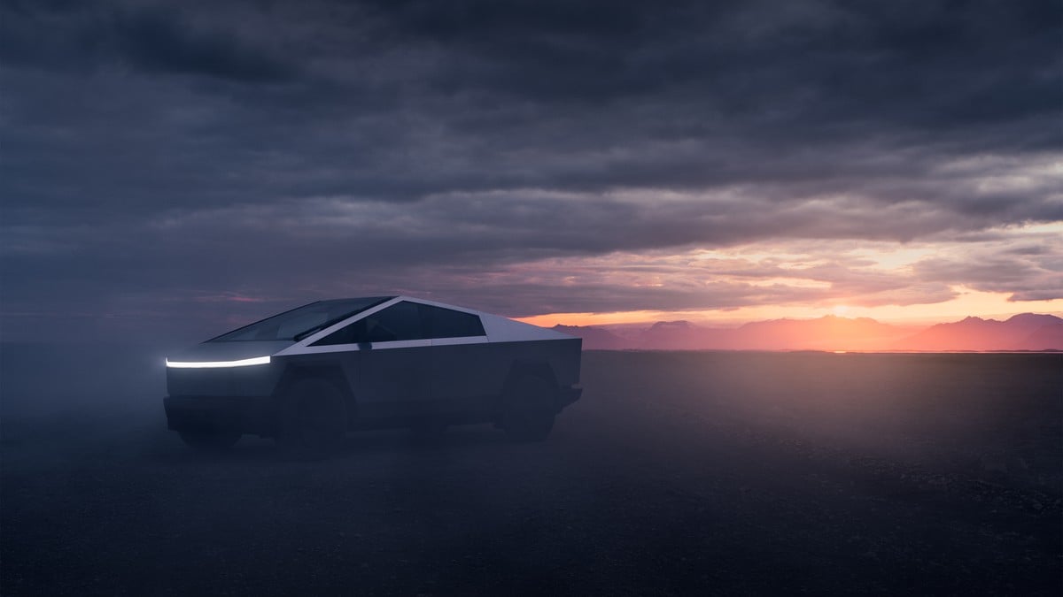 A 2025 Tesla Cybertruck parked in a foggy landscape at sunset, with dramatic clouds and mountain silhouettes in the background.