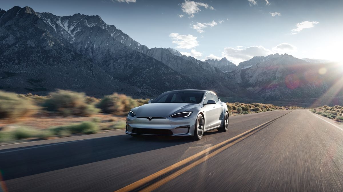 Gray 2025 Tesla Model S Driving on Country Road, mountains in background, double-yellow lines on road.