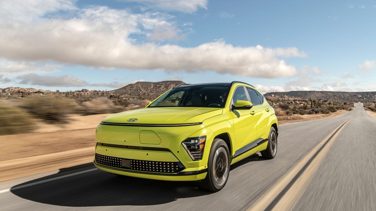 A bright green 2025 Hyundai Kona EV drives on an empty road with a rocky landscape and blue sky in the background, showcasing its modern design.