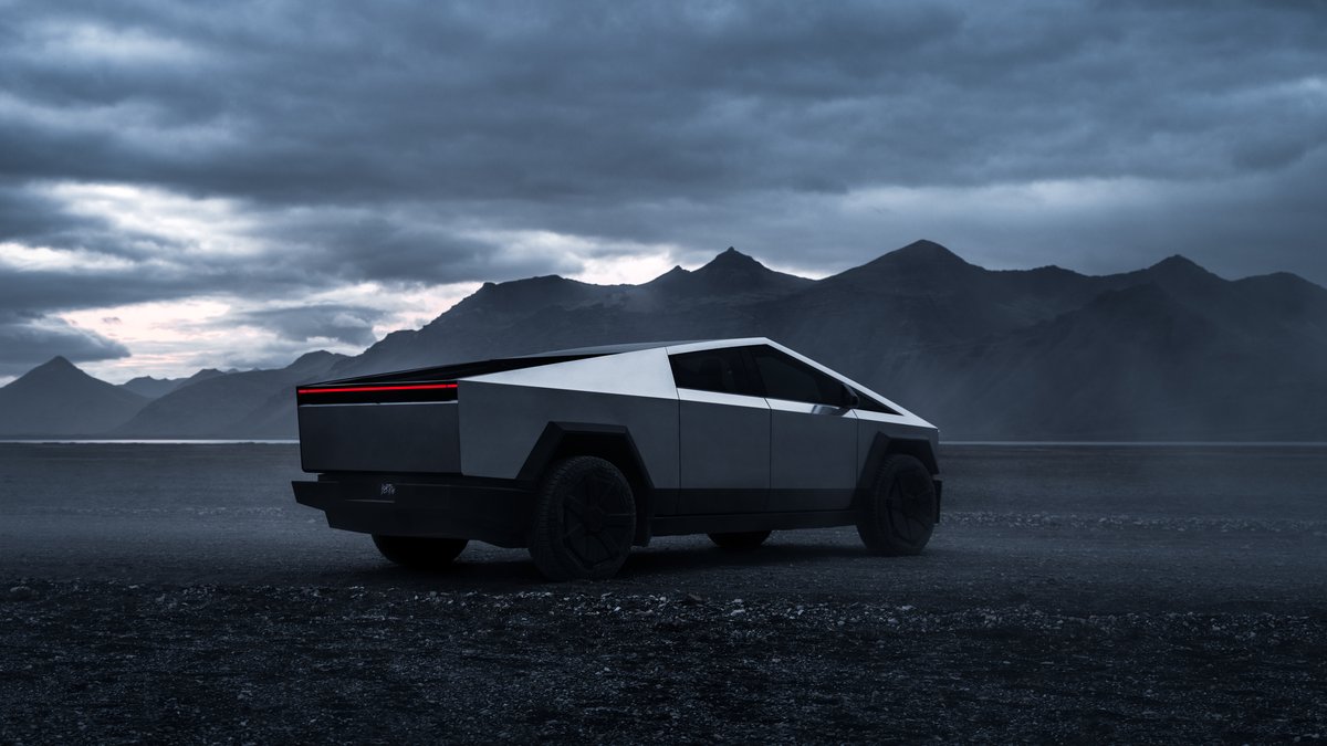 Tesla Cybertruck parked on rocky terrain with dramatic mountain and stormy sky backdrop