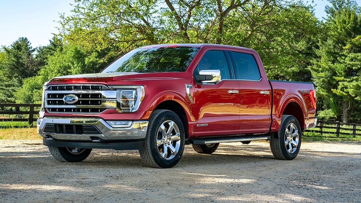 Red Ford F-150 crew cab pickup shown in a front three-quarter view on a gravel driveway.