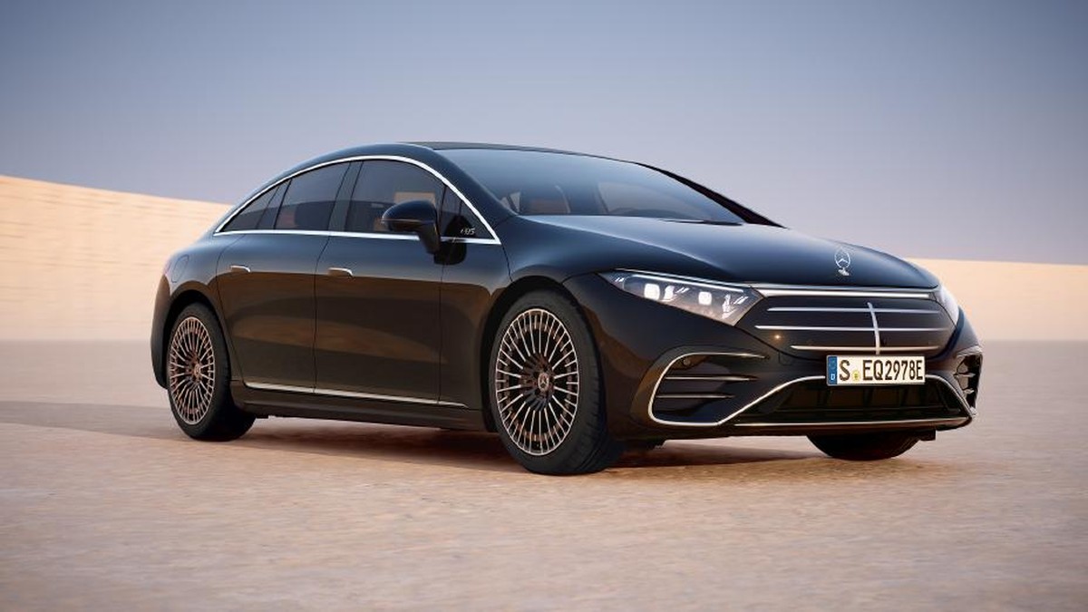A sleek black Mercedes EQS electric sedan parked on sandy terrain, showcasing modern design and luxury styling.