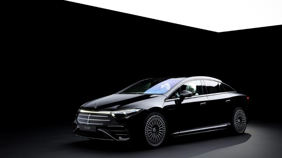 A sleek black Mercedes EQS sedan showcased under dramatic lighting against a dark background, emphasizing its luxury and design.