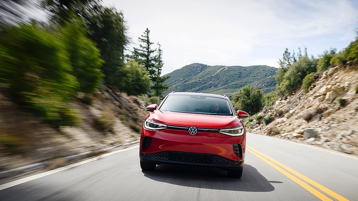 Red Volkswagen ID.4 driving toward the camera on a winding mountain road.