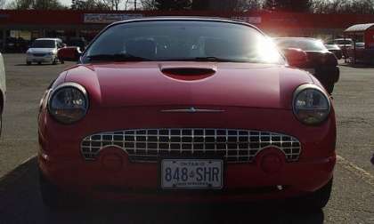 Red Ford Thunderbird (Canadian), model year 200x(?), front view taken at hood-level; sunlight from upper-left, glinting off the paint, chrome, & windshield.